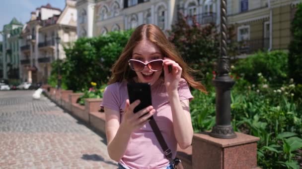 Krásná mladá žena turista v centru města držící telefon - Ano vítězné gesto — Stock video