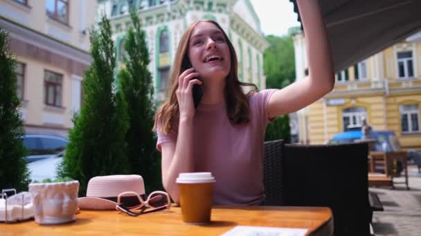 Giovane donna che parla al telefono in un caffè su una terrazza estiva — Video Stock