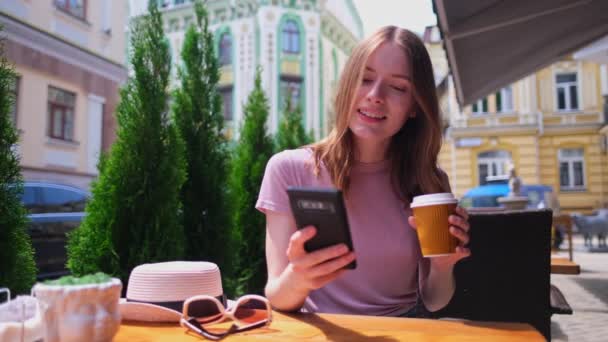 Mujer joven hablando por teléfono en un café en una terraza de verano — Vídeo de stock