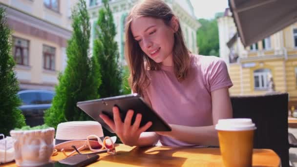 Mujer joven usando tableta PC en un café en una terraza de verano — Vídeo de stock