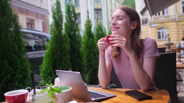 Молода жінка розмовляє по телефону в кафе на літній терасі — стокове відео