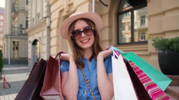 Молода жінка з сумками, що ходять у місті в літній день — стокове відео