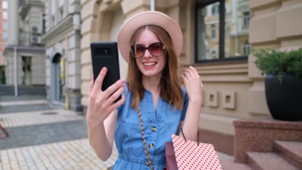 Mujer joven con bolsas de compras caminando en una ciudad en el día de verano — Vídeos de Stock