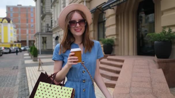 Mujer joven con bolsas de compras caminando en una ciudad en el día de verano — Vídeo de stock