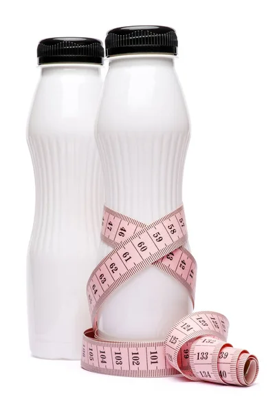 Чиста порожня біла пластикова пляшка йогурту або молока і вимірювальна стрічка ізольована на білому тлі з відсічним контуром — стокове фото