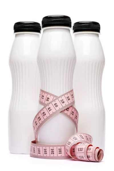 Чиста порожня біла пластикова пляшка йогурту або молока і вимірювальна стрічка ізольована на білому тлі з відсічним контуром — стокове фото