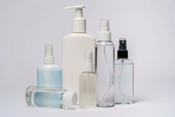 Gruppe von Händedesinfektionsspray oder Flüssigseifenflaschen auf hellgrauem Hintergrund — Stockfoto