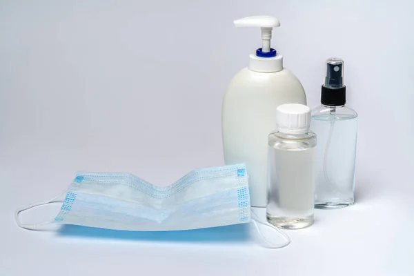Bouteille de lotion, désinfectant ou savon liquide et masque de protection sur fond gris clair — Photo
