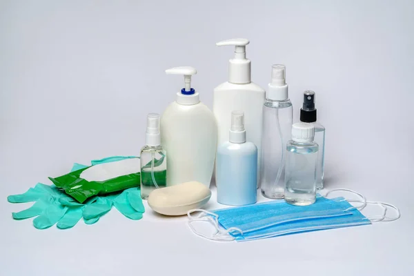 Egy üveg krém, fertőtlenítő vagy folyékony szappan, gumikesztyű és védő maszk világosszürke háttér felett — Stock Fotó