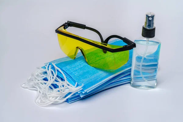 Flesje lotion, reinigingsmiddel of vloeibare zeep, beschermmasker en bril over lichtgrijze ondergrond — Stockfoto