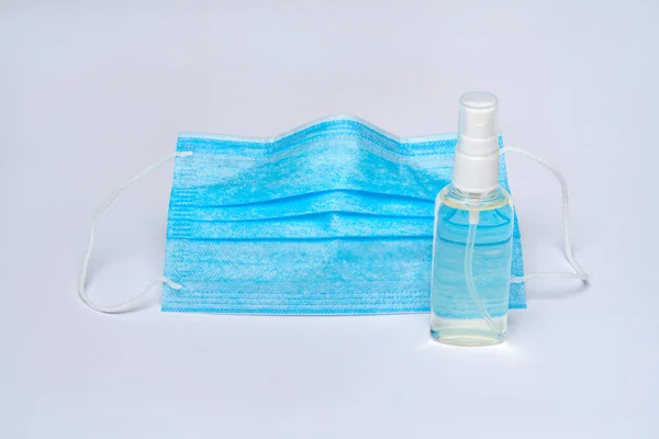 Botol lotion, pembersih atau sabun cair dan masker pelindung di atas latar belakang abu-abu muda — Stok Foto