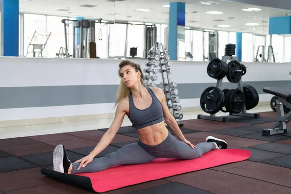 Tanara femeie stretching exercitarea în club de fitness — Fotografie, imagine de stoc