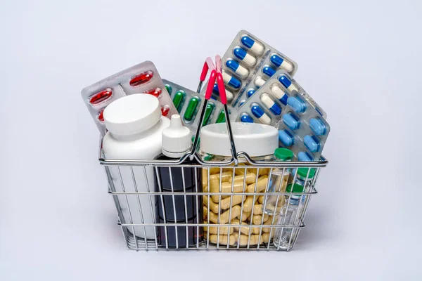 Shopping basket cart full of pills and medical supplies over light grey background — Stock Photo, Image