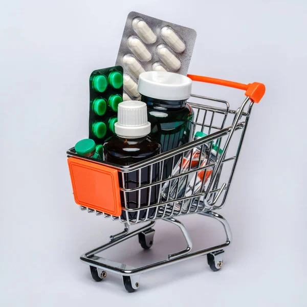 Kundvagn med full av medicinska piller eller vitaminer över ljusgrå bakgrund — Stockfoto