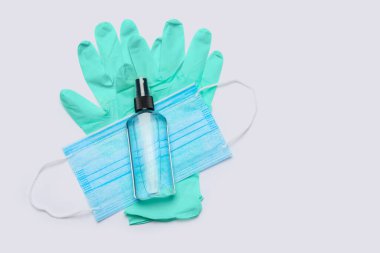 flat layout of hygiene items - latex gloves, mask and hand sanitizer over light grey background clipart