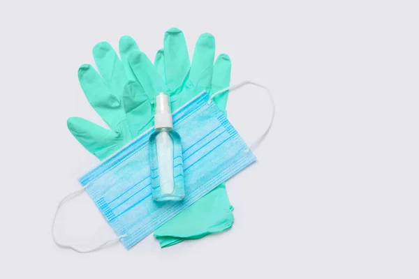 Layout plano de itens de higiene luvas de látex, máscara e higienizador de mão sobre fundo cinza claro — Fotografia de Stock