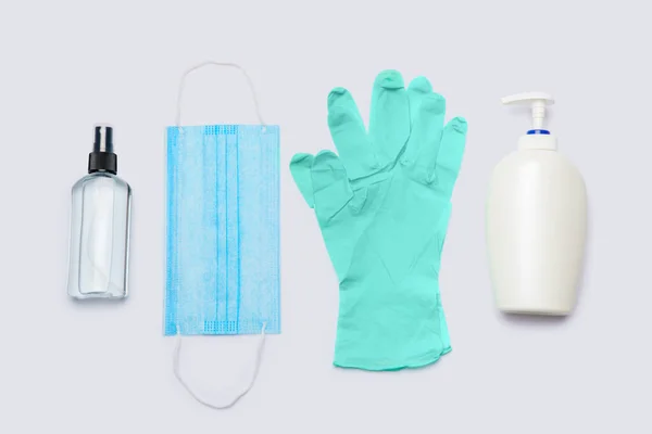 Higiéniai termékek lapos elrendezése - latex kesztyű, maszk és kézfertőtlenítő világosszürke háttér felett — Stock Fotó