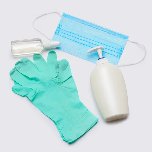 Flat layout of hygiene items - latex gloves, mask and hand sanitizer over light grey background — Stock Photo, Image