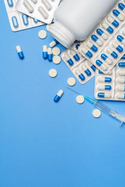 Coronavirus koruma kavramı - haplar, kapsüller, tabletler ve mavi arka planda şırınga — Stok fotoğraf