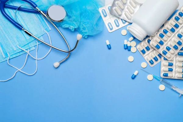 Coronavirus protection concept - stethoscope, protective mask, pills, syringe on blue background. — Stock Photo, Image