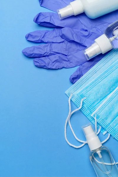 Botella de loción, desinfectante o jabón líquido, guantes de goma de látex, sombrero y máscara protectora sobre fondo azul - diseño plano — Foto de Stock