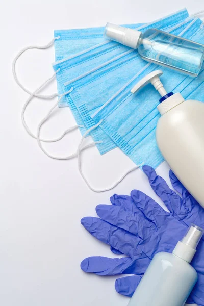 Bottiglia di lozione, disinfettante o sapone liquido, guanti di gomma di lattice, cappello e maschera protettiva su fondo grigio chiaro layout piatto — Foto Stock