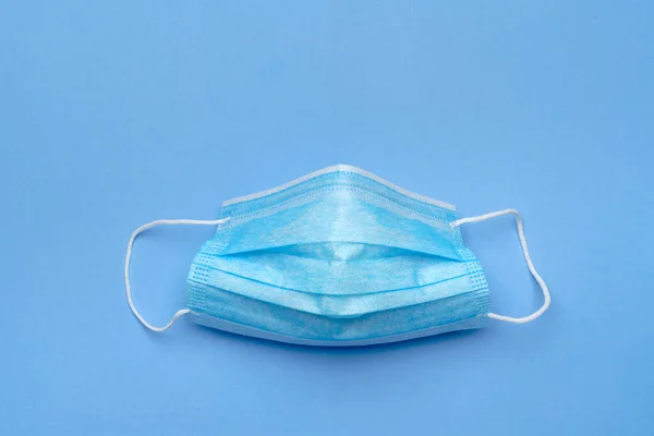 Wegwerp blauw medisch gezichtsmasker op blauwe achtergrond — Stockfoto