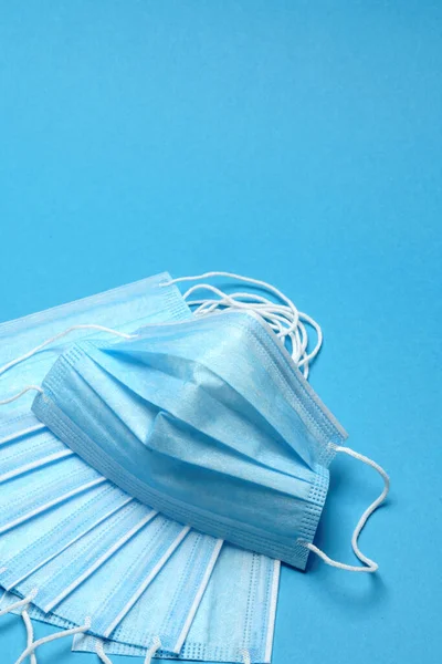 Одноразовая синяя медицинская маска на синем фоне — стоковое фото