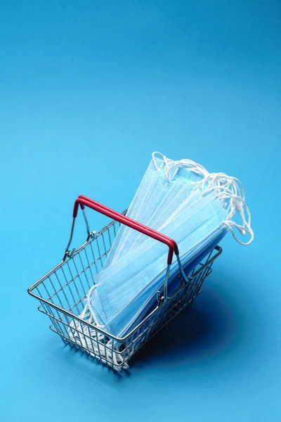 安全和网上购物检疫的概念。蓝色背景下有防护口罩的购物篮 — 图库照片