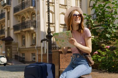 Beautiful Young Woman tourist Pleasant with city map and suitcase in the City Center clipart