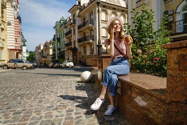 Красивая молодая туристка с кофе на вынос в центре города разговаривает по телефону — стоковое фото