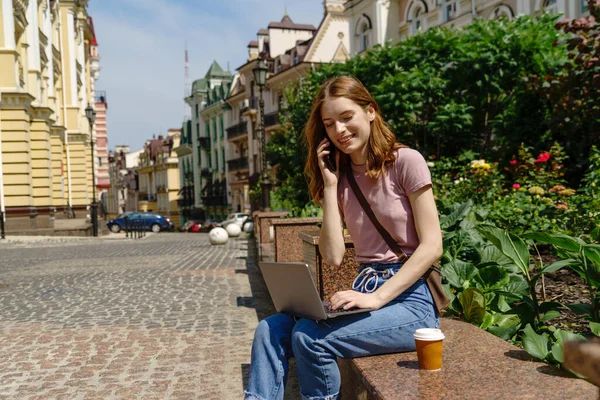 Bella giovane donna turista con caffè da asporto nel centro della città utilizzando il computer portatile — Foto Stock