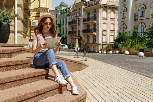 Schöne junge Frau Touristin Angenehm mit Stadtplan sitzt auf Treppen im Stadtzentrum — Stockfoto