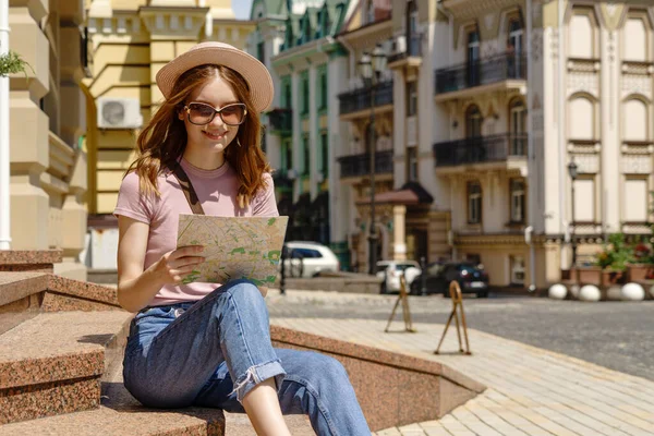 Bella Giovane Donna turista Piacevole con mappa della città seduta sulle scale nel centro della città — Foto Stock
