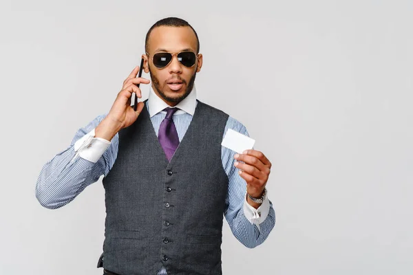 Um jovem empresário africano usando seu smartphone para fazer compras online enquanto segura seu cartão de crédito — Fotografia de Stock