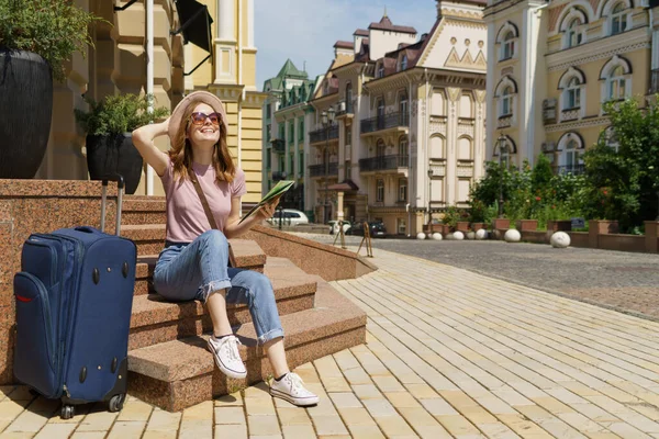 美しい若い女性の観光客階段に座っている都市の地図やスーツケースと快適な — ストック写真
