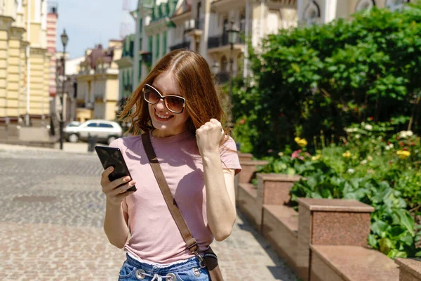 Bella giovane donna turista nel centro della città in possesso di telefono e rendendo sì vincere gesto — Foto Stock