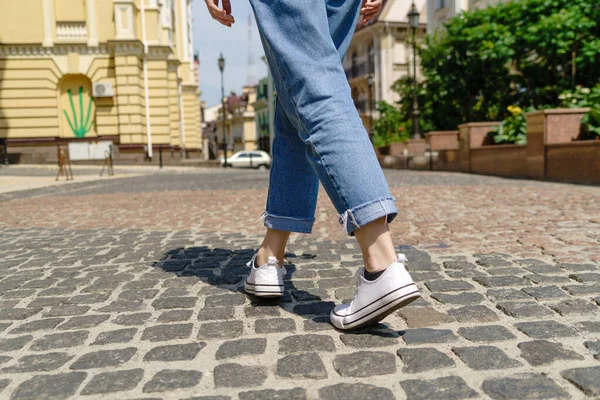 Close up of person walking on paving stone street at summer day