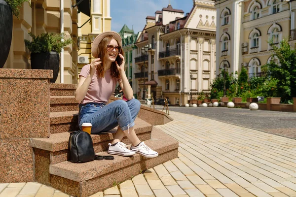 Bella giovane donna turista con caffè da asporto seduto sulle scale utilizzando smartphone — Foto Stock