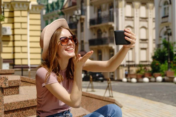 Hermosa mujer joven turista con café para llevar sentado en las escaleras con teléfono inteligente —  Fotos de Stock