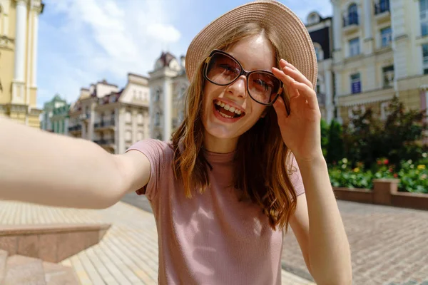 Mujer bastante joven en gafas haciendo selfie en el centro de la ciudad —  Fotos de Stock