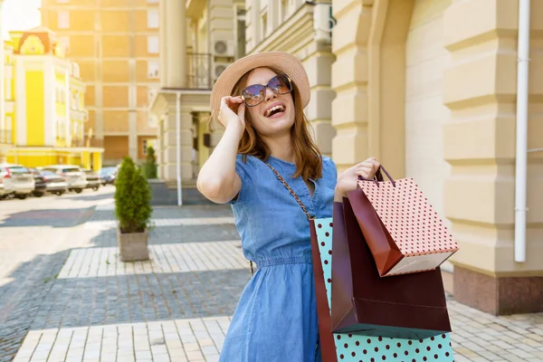 쇼핑 가방을 들고 여름철에 도시를 걷고 있는 젊은 여자 — 스톡 사진