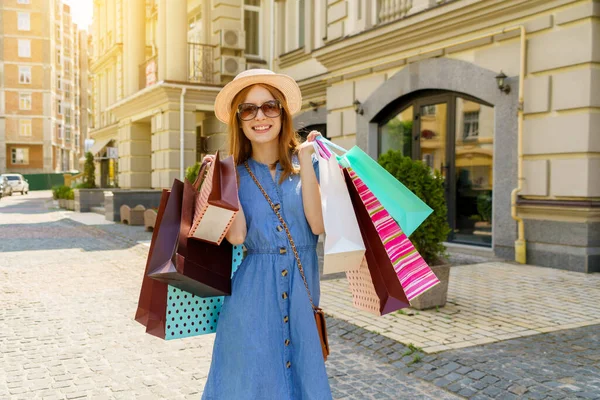 Mujer joven con bolsas de compras caminando en una ciudad en el día de verano —  Fotos de Stock