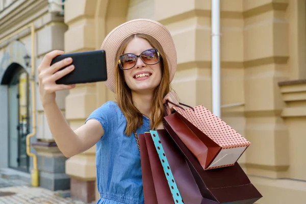 Fiatal nő bevásárló táskák, hogy szelfi séta a városban a nyári napon — Stock Fotó