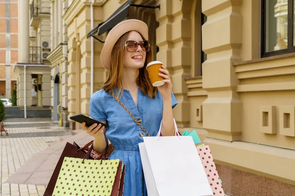 Mladá žena s nákupními taškami procházky ve městě v letní den — Stock fotografie