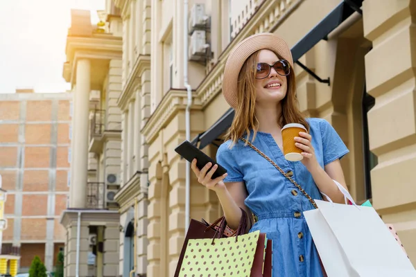 Mujer joven con bolsas de compras caminando en una ciudad en el día de verano —  Fotos de Stock