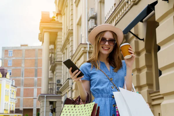 Mujer joven con bolsas de compras caminando en una ciudad en el día de verano — Foto de Stock