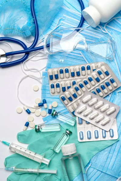 Coronavirus protection concept - stethoscope, hat, goggles, syringe and protective mask, pills, syringe on blue background — Stock Photo, Image