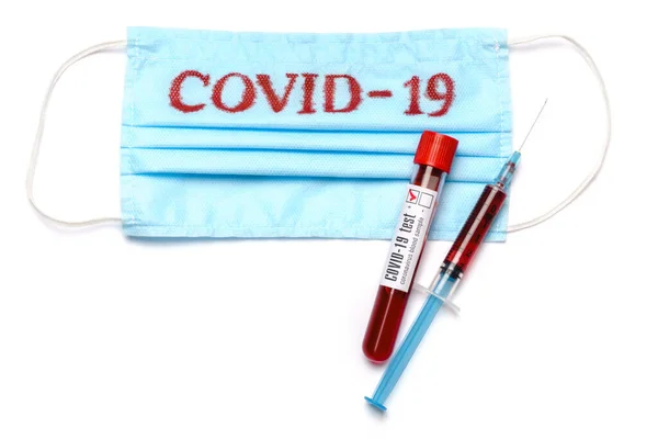 Трубка для анализа крови, шприц и медицинская защитная маска с табличкой COVID-19 на белом фоне с вырезкой — стоковое фото