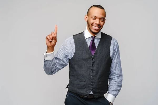 Afroamerikanischer Geschäftsmann zeigt mit dem Finger auf grauen Hintergrund — Stockfoto